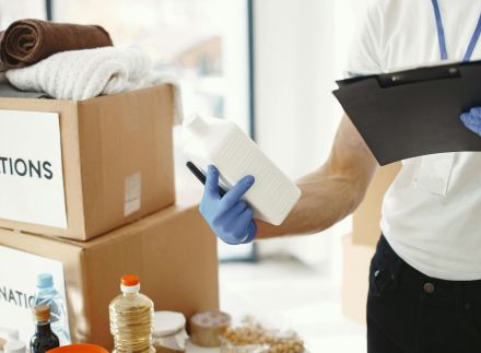 Focused volunteer in gloves sorting donation supplies in a community center.